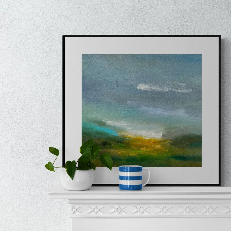 Sunlit Breath small abstract landscape painting framed sitting on a mantelpiece with mug and plant in front by Mary Burtenshaw