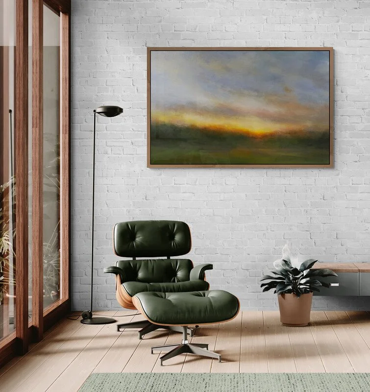 Impressionist landscape painting hanging on a white brick wall above a armchair