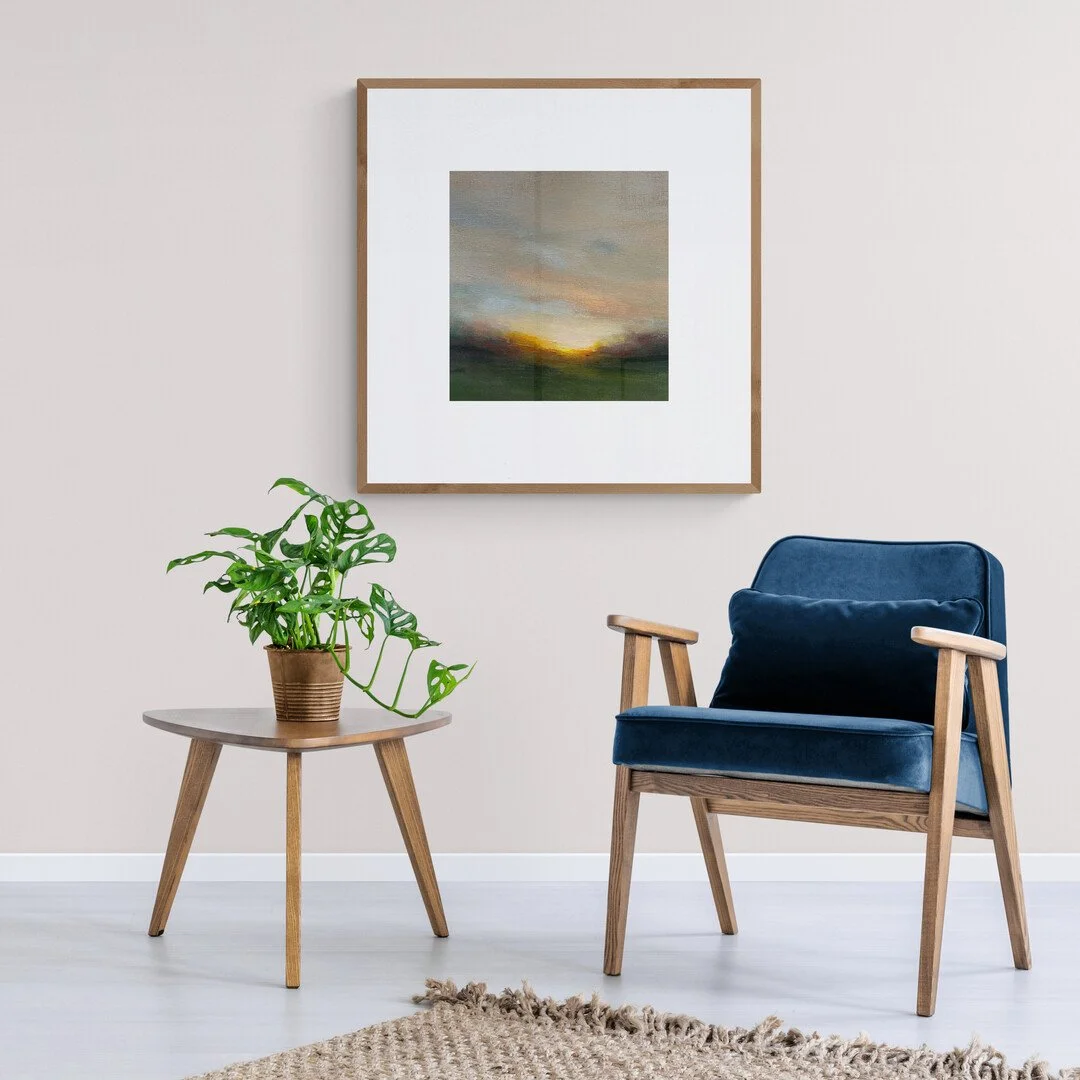 Small abstract landscape painting styled on a modern living room wall above a armchair and table and plant