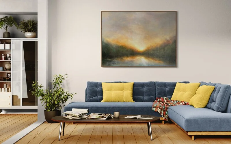 Impressionist river scene in living room setting above a large blue sofa and accent yellow cushions