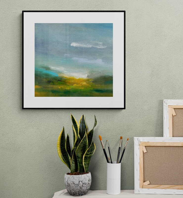 Artists table with plant and 'Sunlit Breath' abstract landscape painting on the wall.