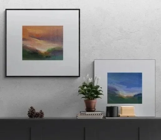 Two small spontaneous landscapes on paper one framed and one mounted sitting on a shelf and the framed painting hanging above the shelf