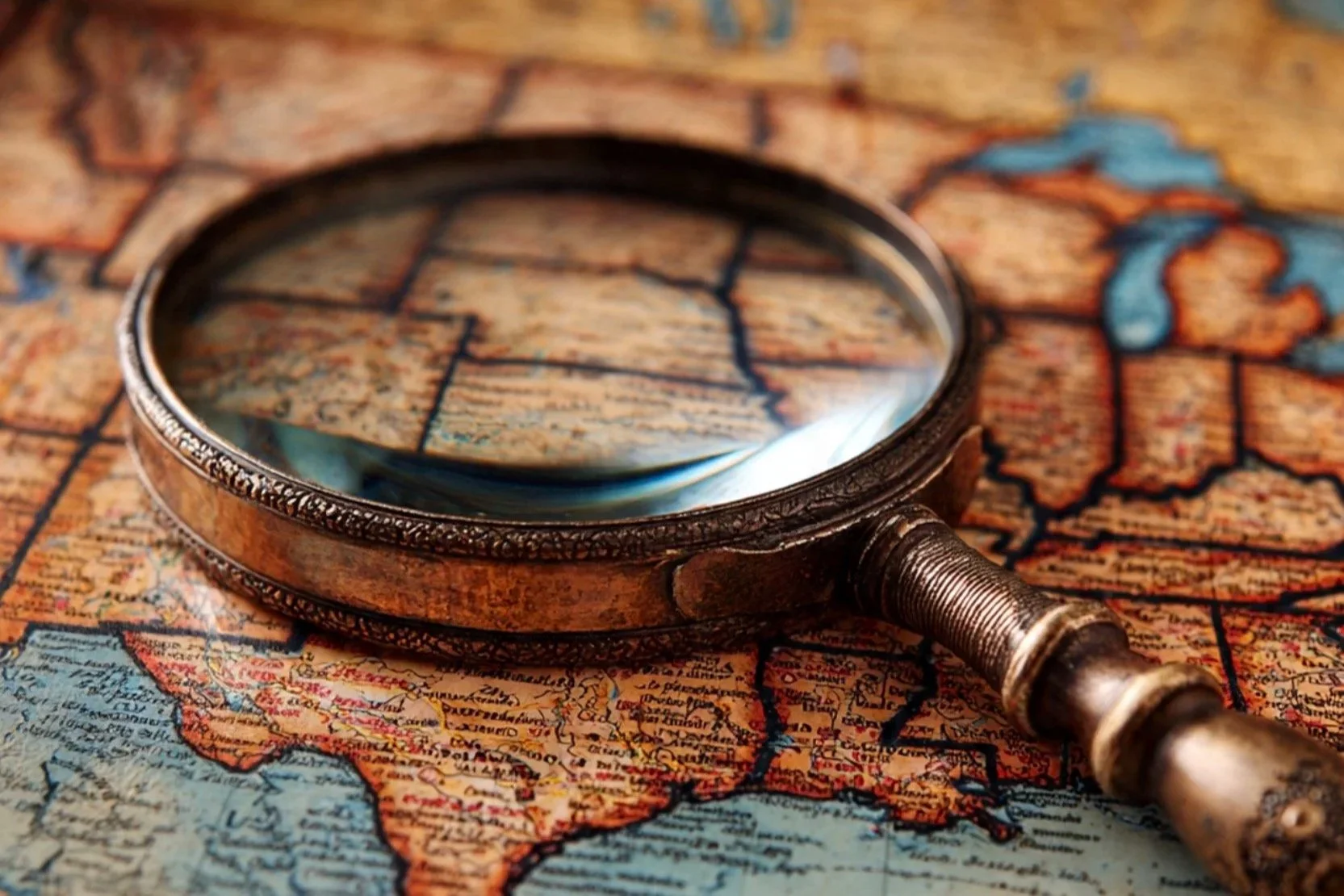 An antique magnifying glass placed on a vintage map of South America.