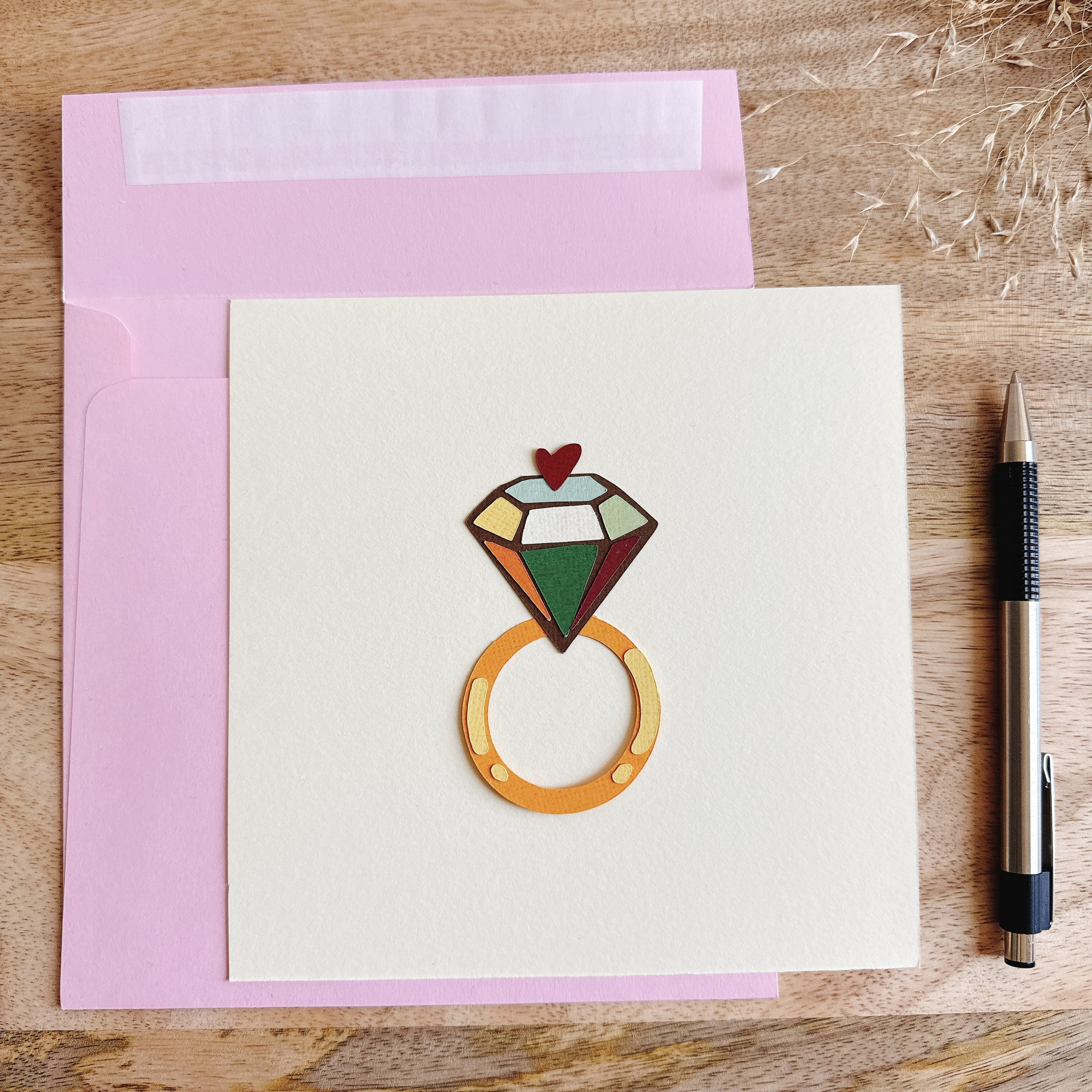 Original papercut collage Golden Loop — 6x6 inch artwork of a colorful ring topped with a red heart. Symbol of love, joy, and eternity.