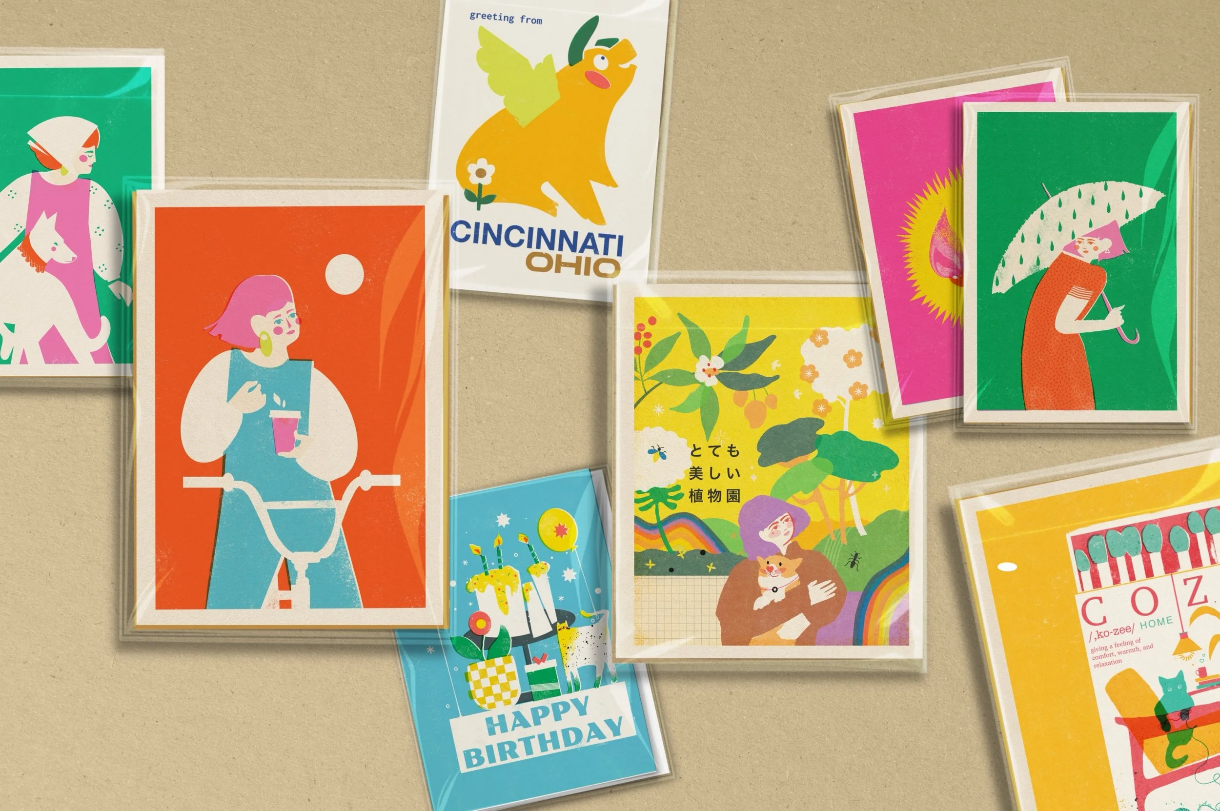 A collection of colorful framed illustration prints displayed together in the VteronikArt studio, featuring playful characters, city scenes, and contemporary artwork.