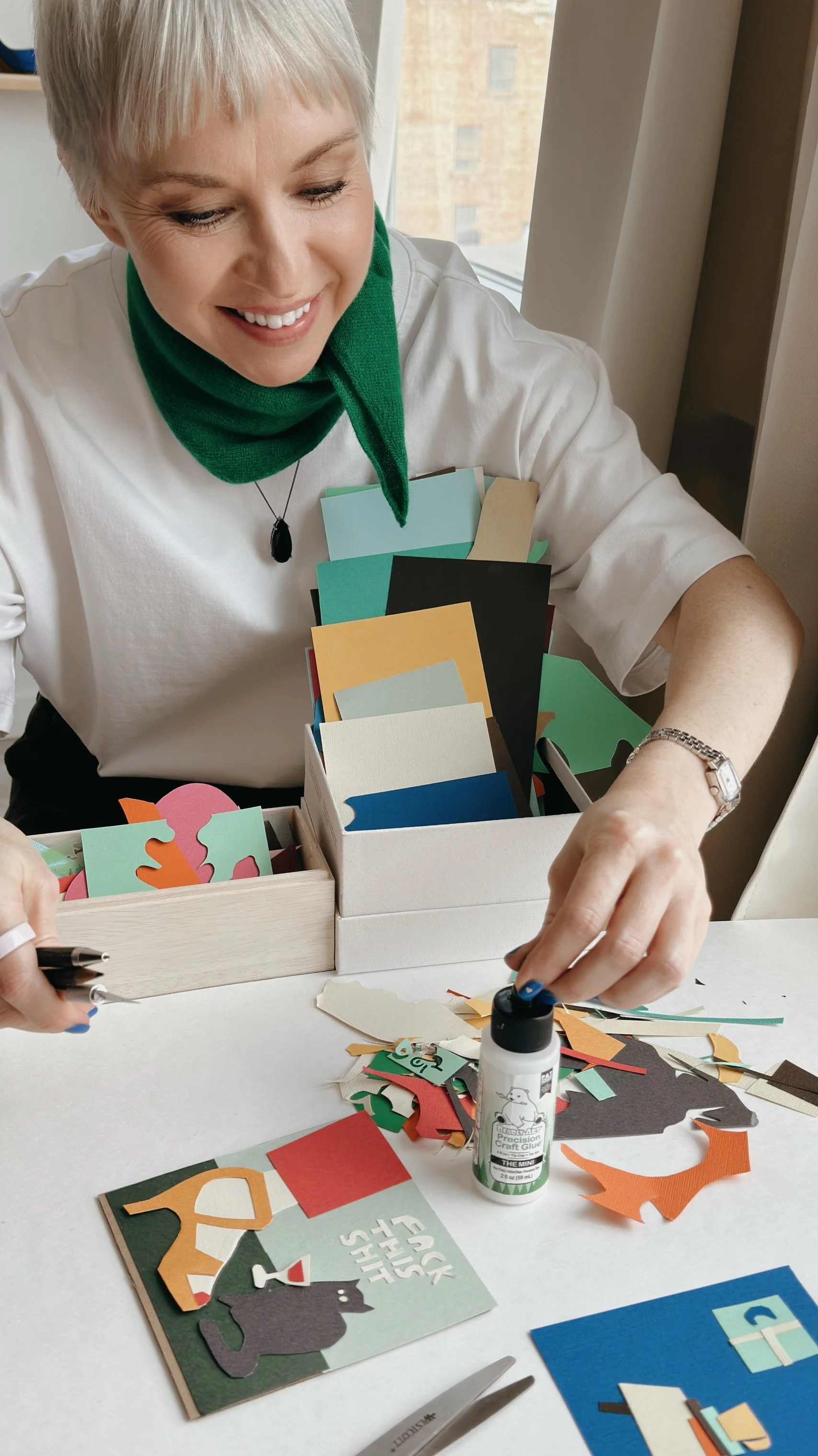 Hand-cutting paper collage elements, artist Veronika Timokhina’s workspace with scissors and paper cutouts.