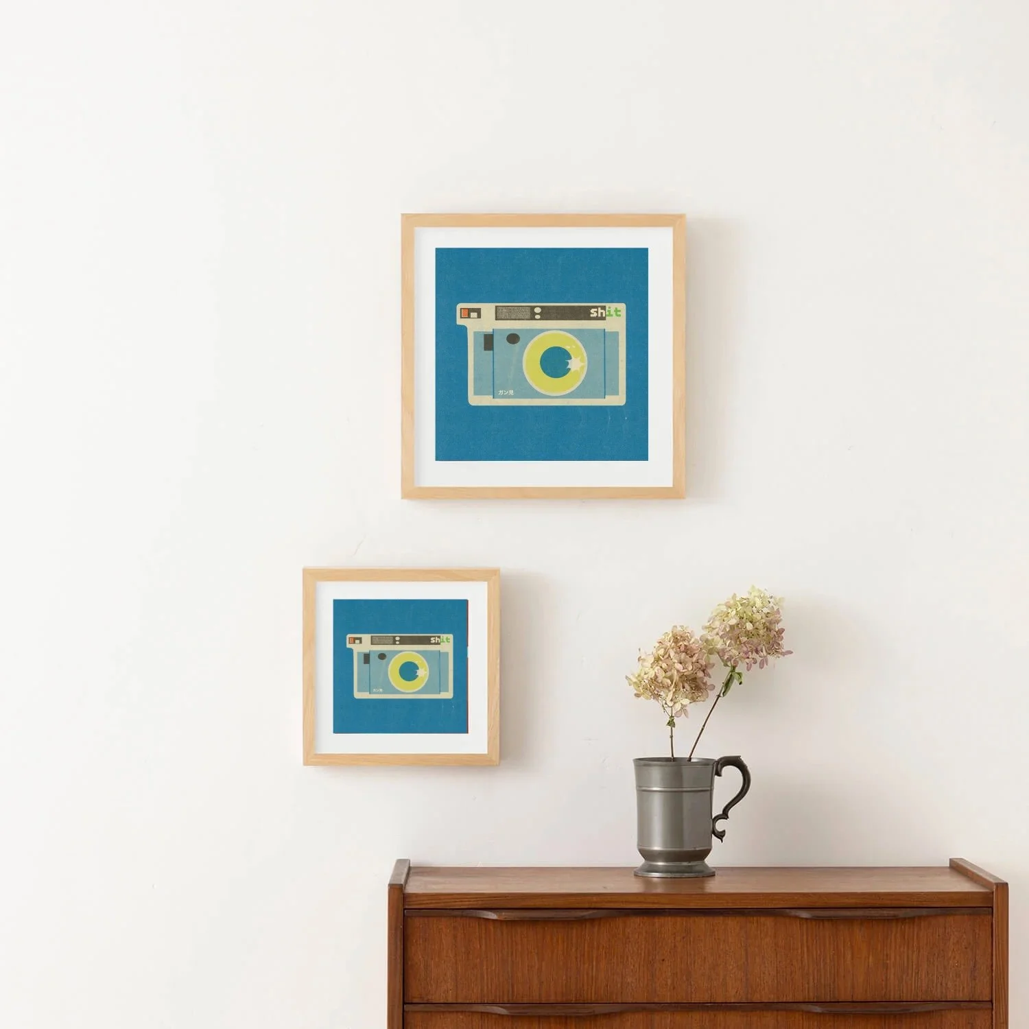 Framed fine art print featuring a retro instant camera with an eye instead of a camera lens. Graphic illustration by Veronika Timokhina displayed in a natural wood frame in interior
