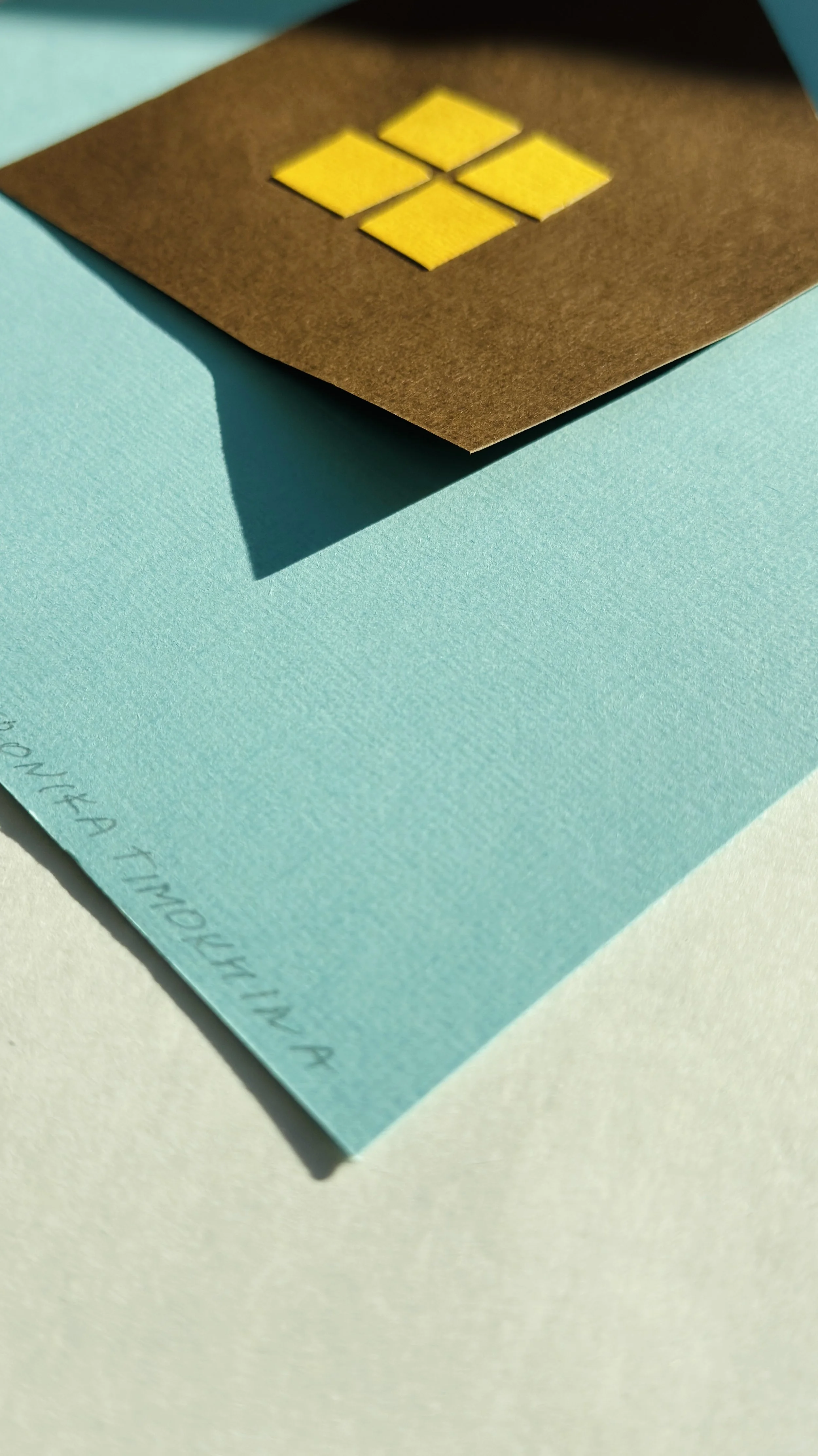 Hand-cut paper collage of home, made from simple geometric shapes, photographed on a dark background, minimalist contemporary paper art