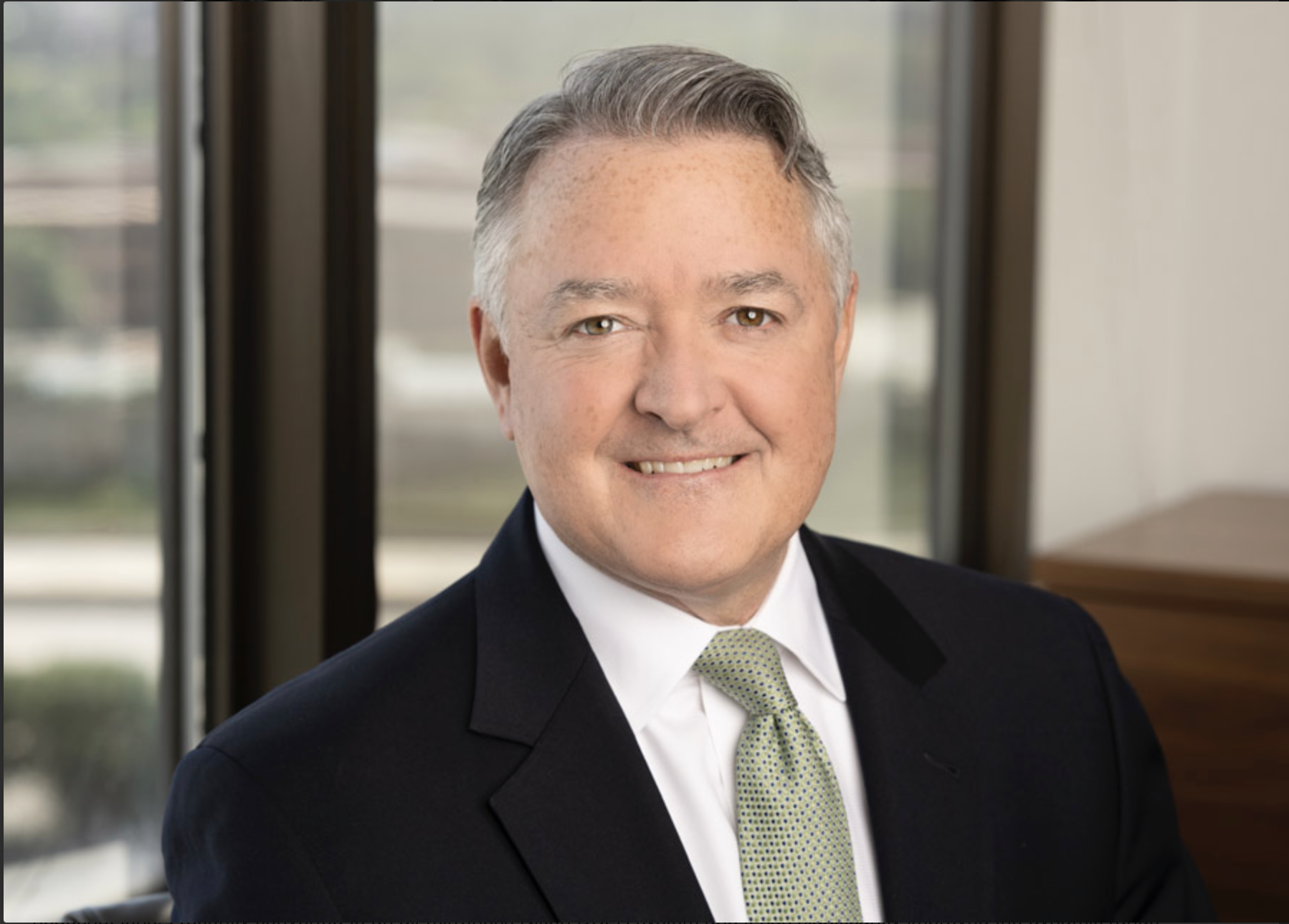 An headshot with a blurred background of a professional Chicago attorney downtown in a high rise