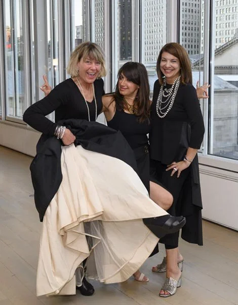 Three women dressed in black, smiling and posing together at a party in the Art Museum