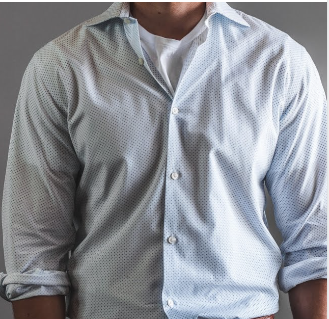 Close-up of a man wearing a white dress shirt with small black dots and a white T-shirt underneath.