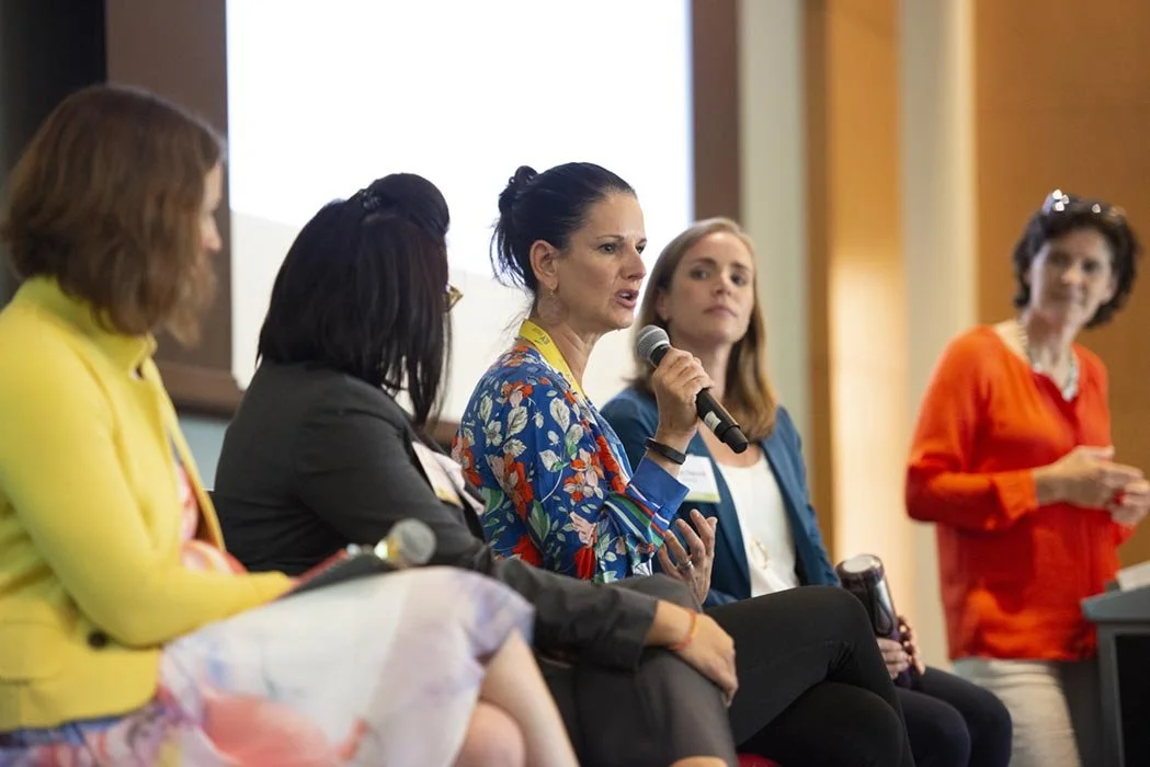 Five women seated on a panel captured at a conference for a professional client.
