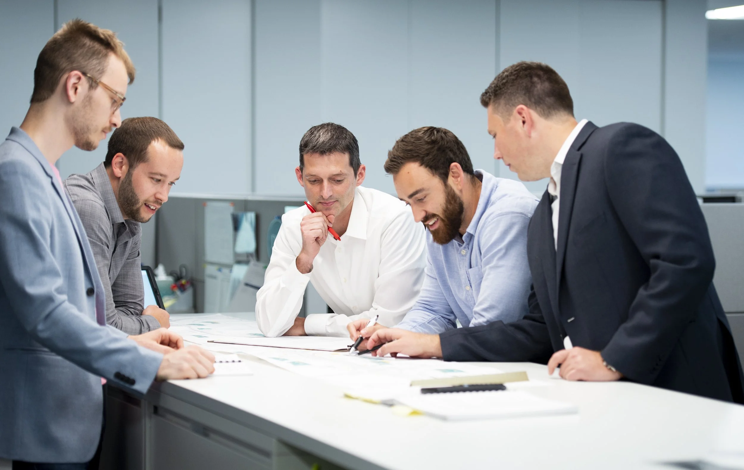 Five businessmen collaborating around a table in an office.