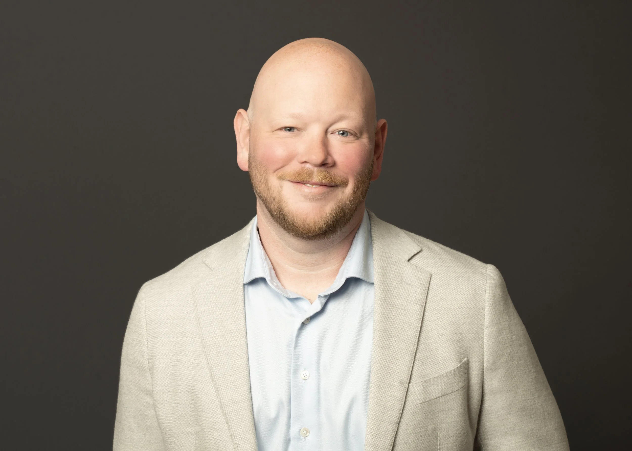 Chicago's best photographer took a headshot of a professional business man on a dark grey background for corporate branding use.