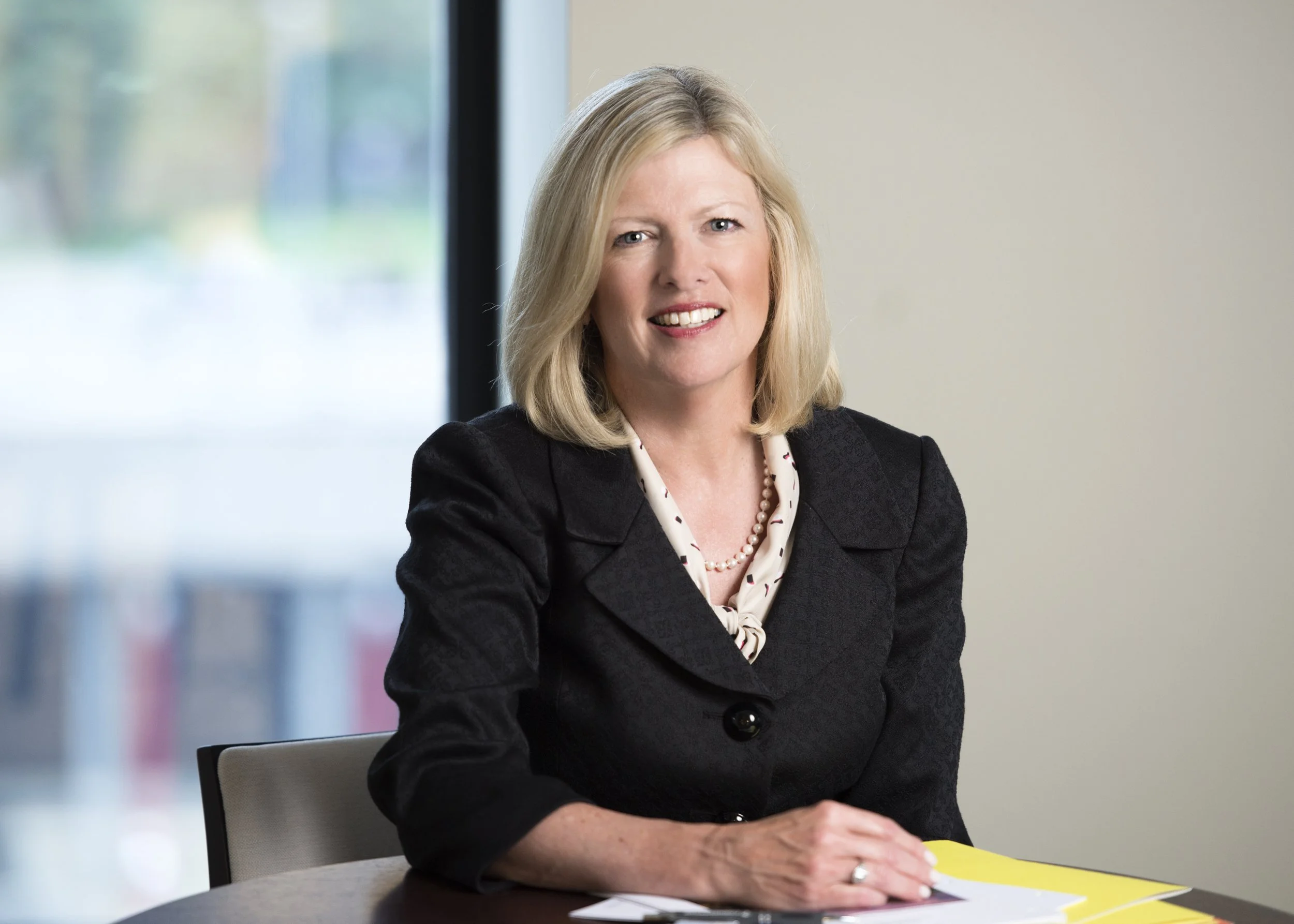 a top Chicago portrait photographer took this photo of a modern woman at her desk in front of a window for the company website and annual report as she is the president and CEO