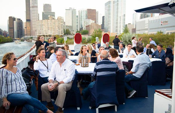 People enjoying a social gathering on a boat with city skyline in the background.