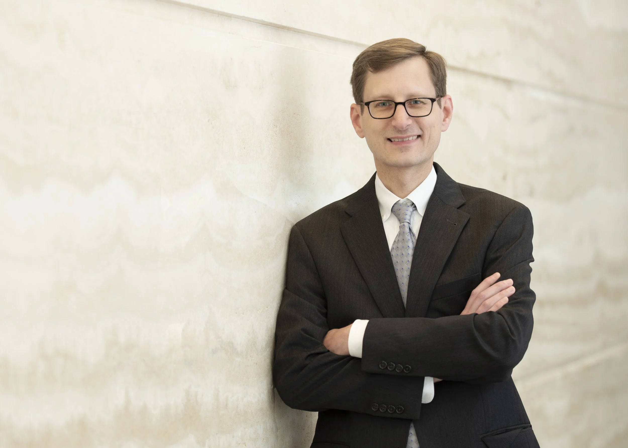 Chicago executive portrait taken for a magazine article about an accounting firm president at an iconic bank downtown with his arms crossed and the marble going out of focus taken by a Chicago photographer