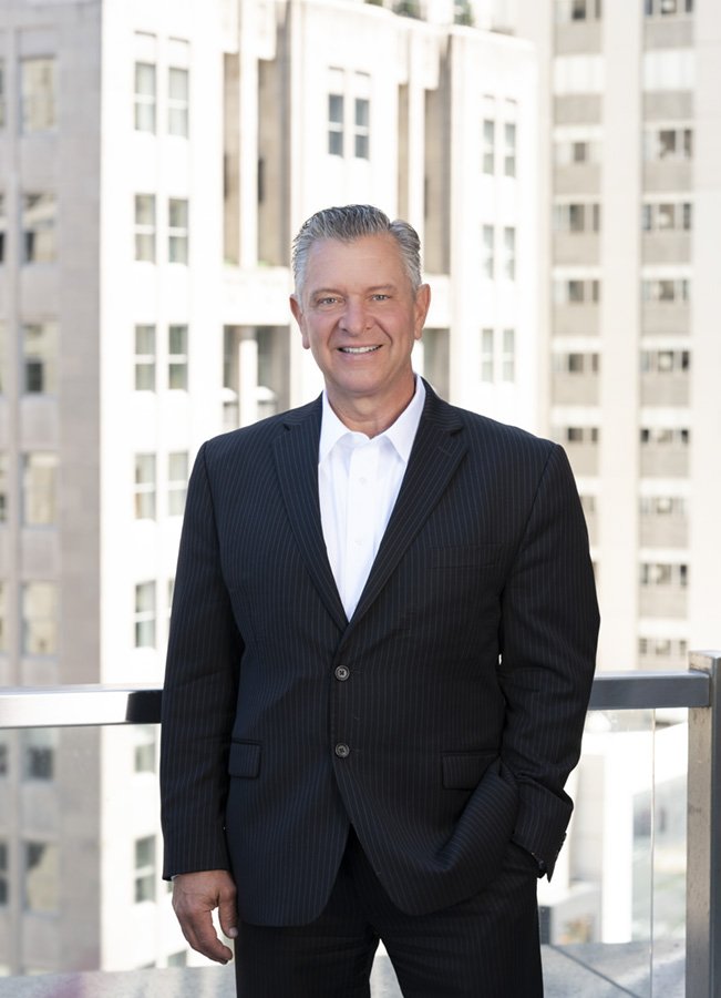 A Chicago portrait photographer took this photo of a realtor. This is an upscale real estate agency on Michigan Avenue with a terrace that overlooks the city. This shows the high end branding by using buildings as the backdrop.