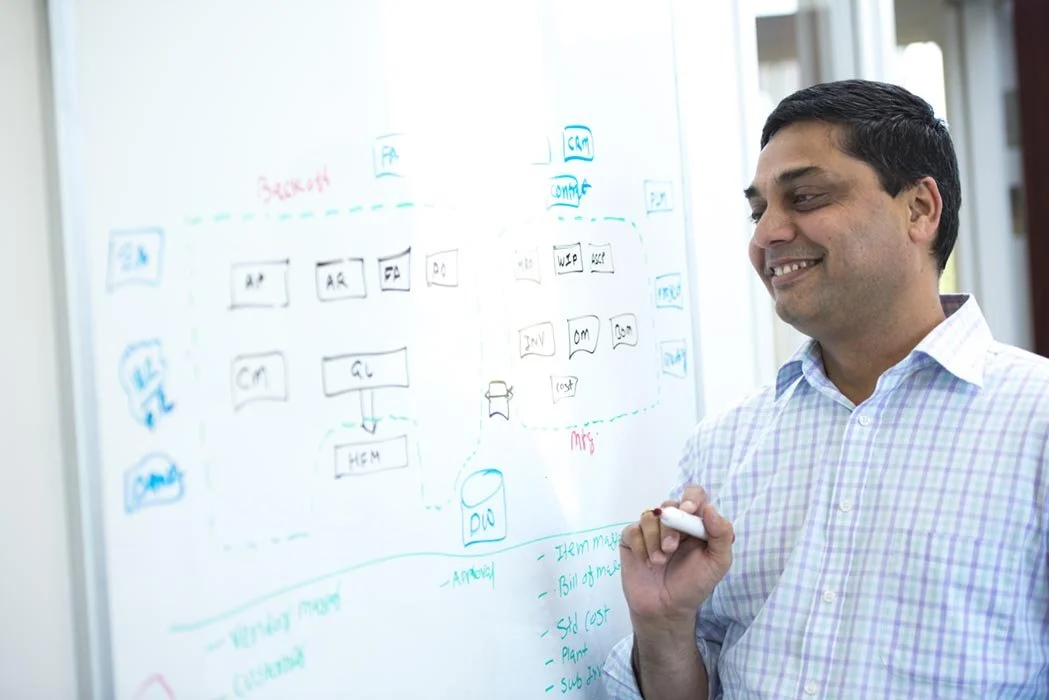 Custom stock photo for health care of a man smiling at whiteboard with diagrams and notes.
