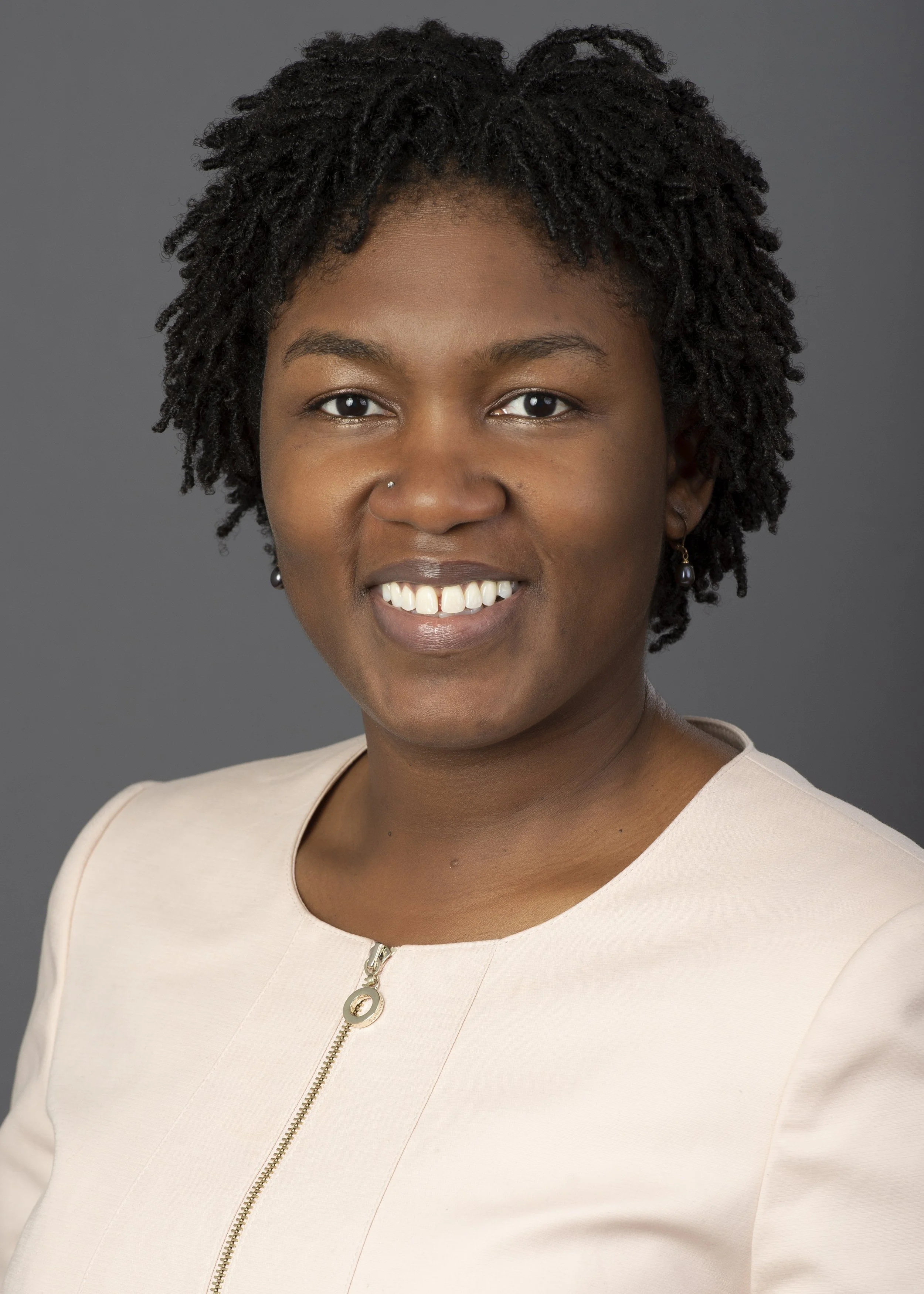 Professional headshot photography of a black woman in a pink dress closely cropped on a gradient dark background. This head shot is lit and photographed by a Chicago photographer.