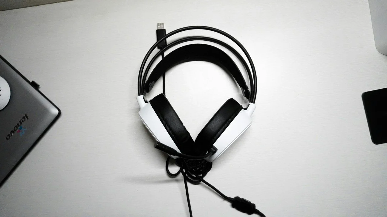 A USB headser on top of a desk with a prtly visible laptop on either side.
