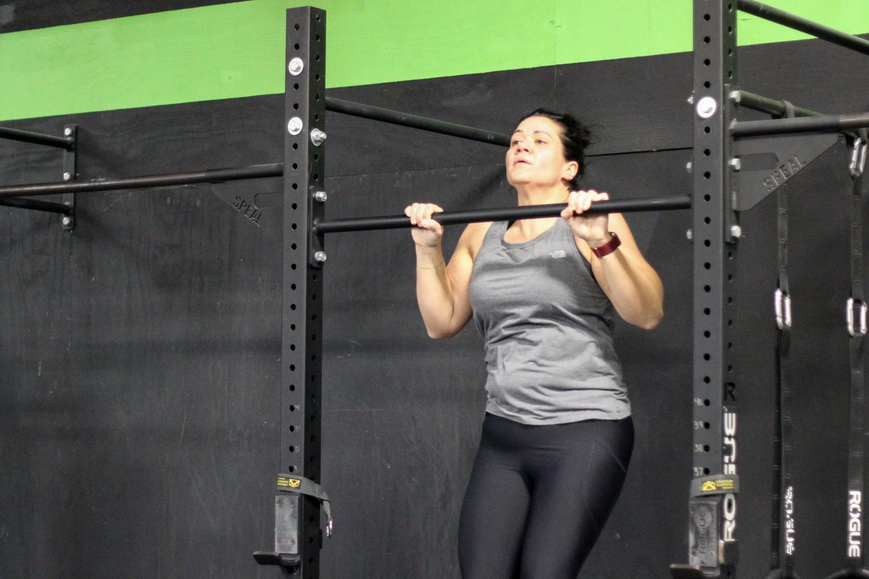 Woman doing a pull-up exercise on a gym pull-up bar in a fitness center.