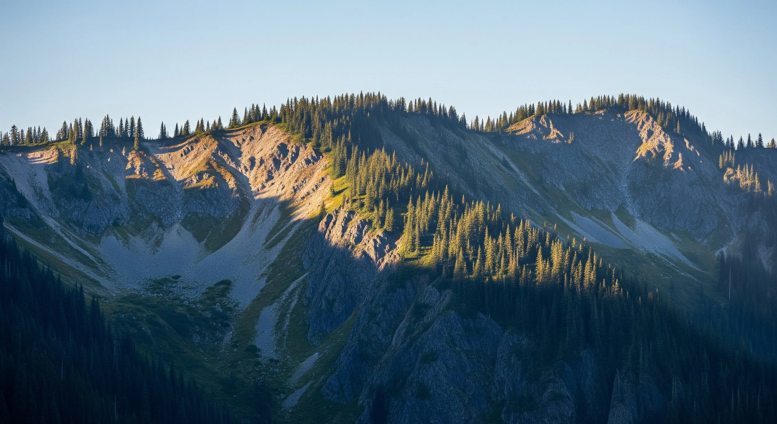 Sunlit mountain ridge above a valley in shadow