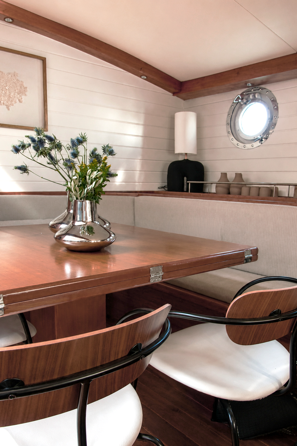 Dining area aboard the classic sailing yacht Alexa of London, featuring a teak dining table, Pavilion AV4 chairs by Andersen & Voll, Georg Jensen vessels and Studio Vourli's bespoke Philokalia lamp.