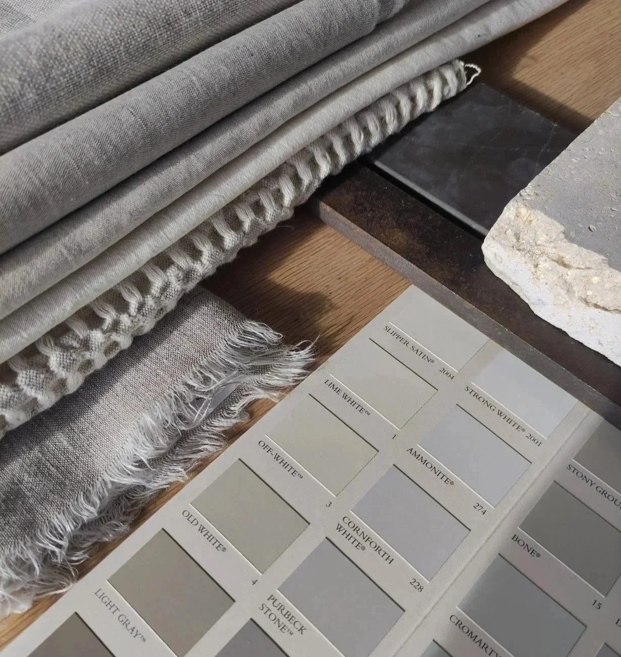 A display of fabric swatches and color samples on a wooden surface, with a selection of textiles on the left and a color chart on the right.