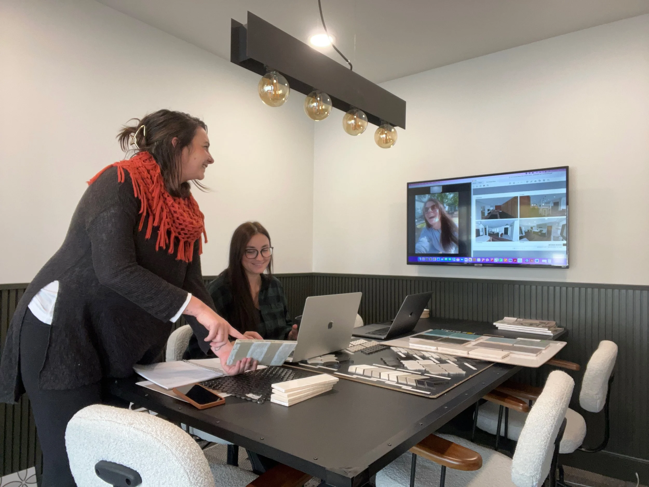 Interior design meeting with team member on zoom and two people in the office surrounded by samples