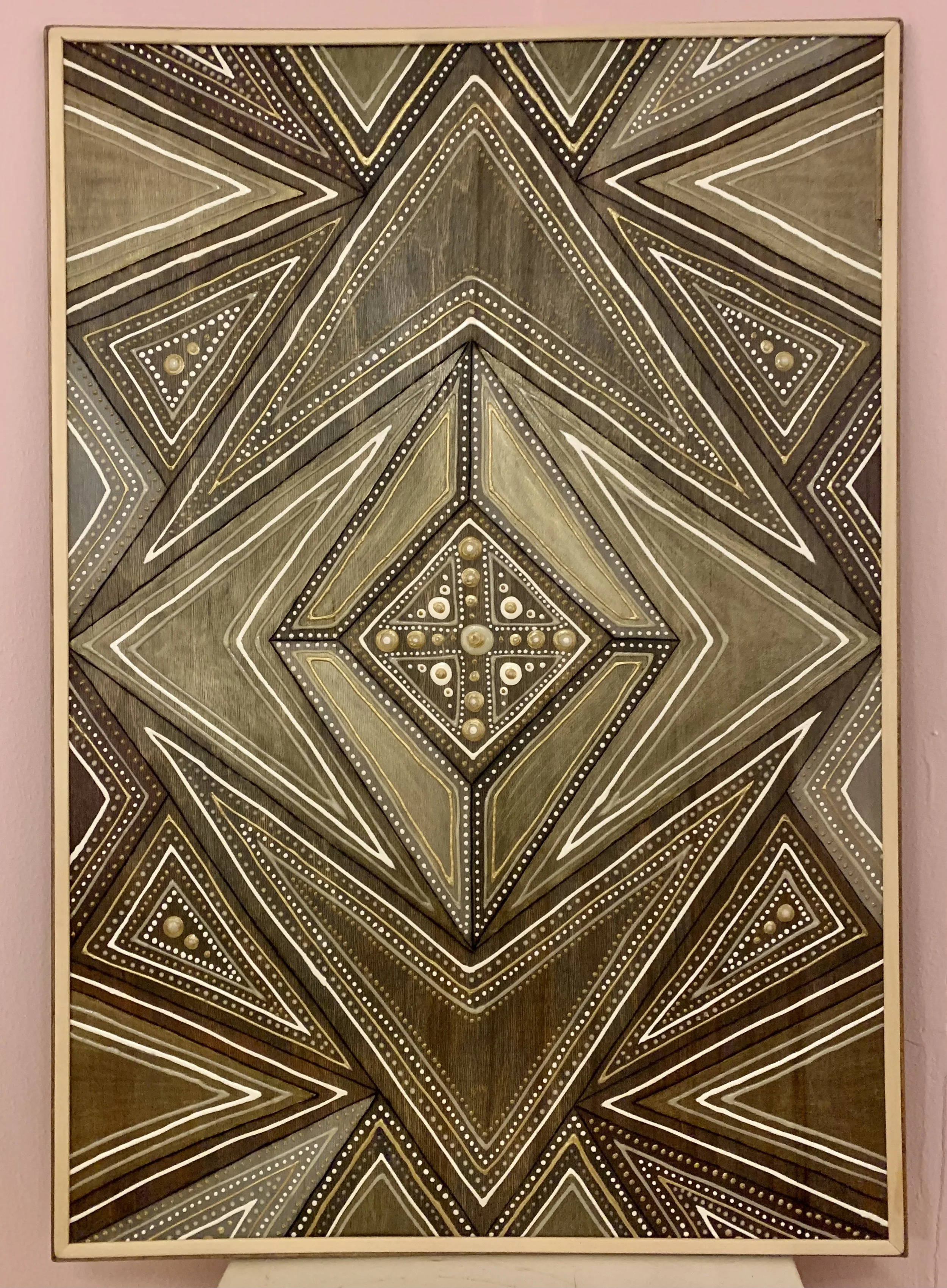 Geometric abstract art with symmetrical patterns and triangles in various shades of brown, white, and gold.