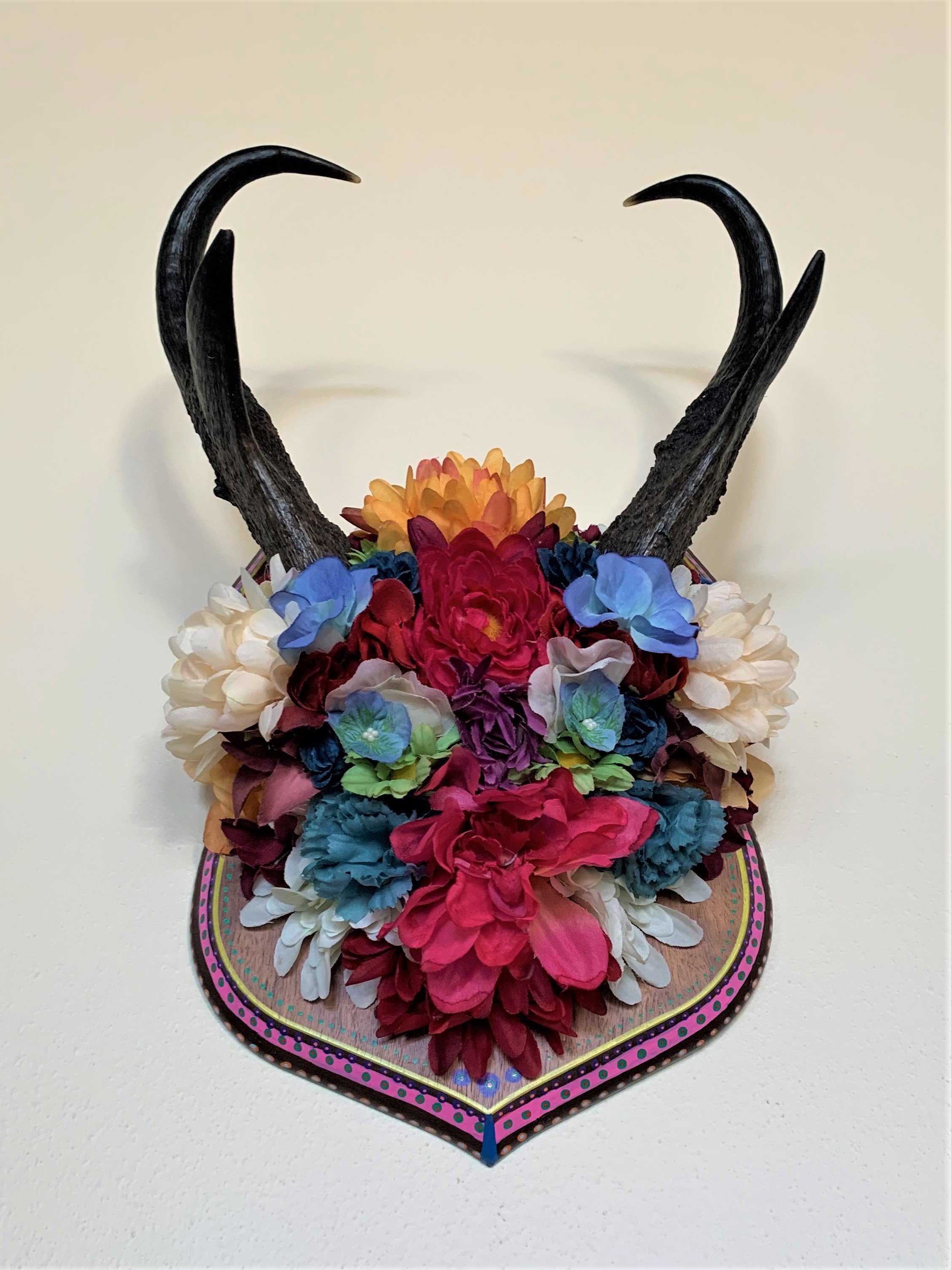 Decorative wall mount with antlers and colorful artificial flowers