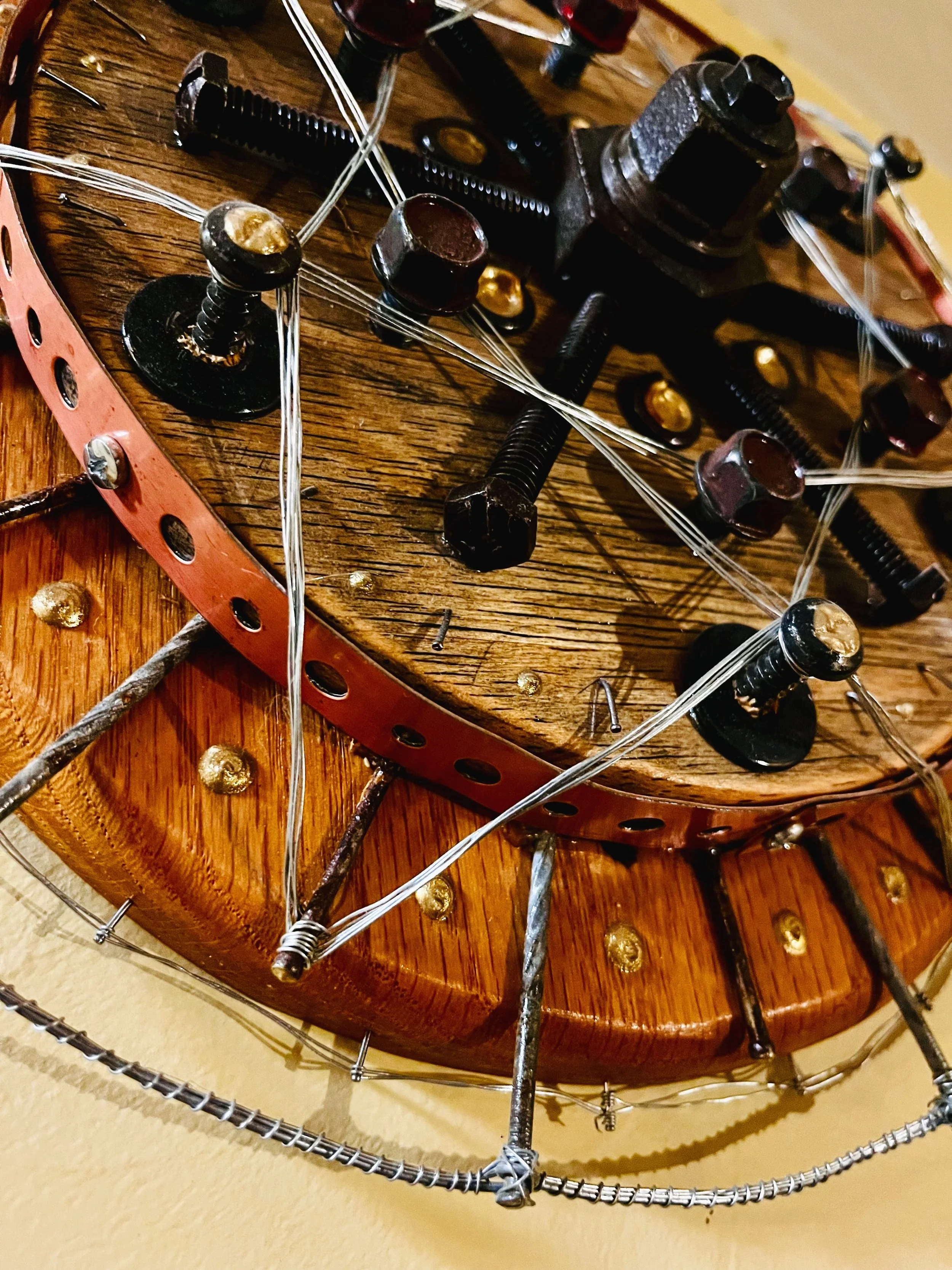 Close-up of a steampunk-style wall decoration featuring metal gears, bolts, and wires on a wooden base.