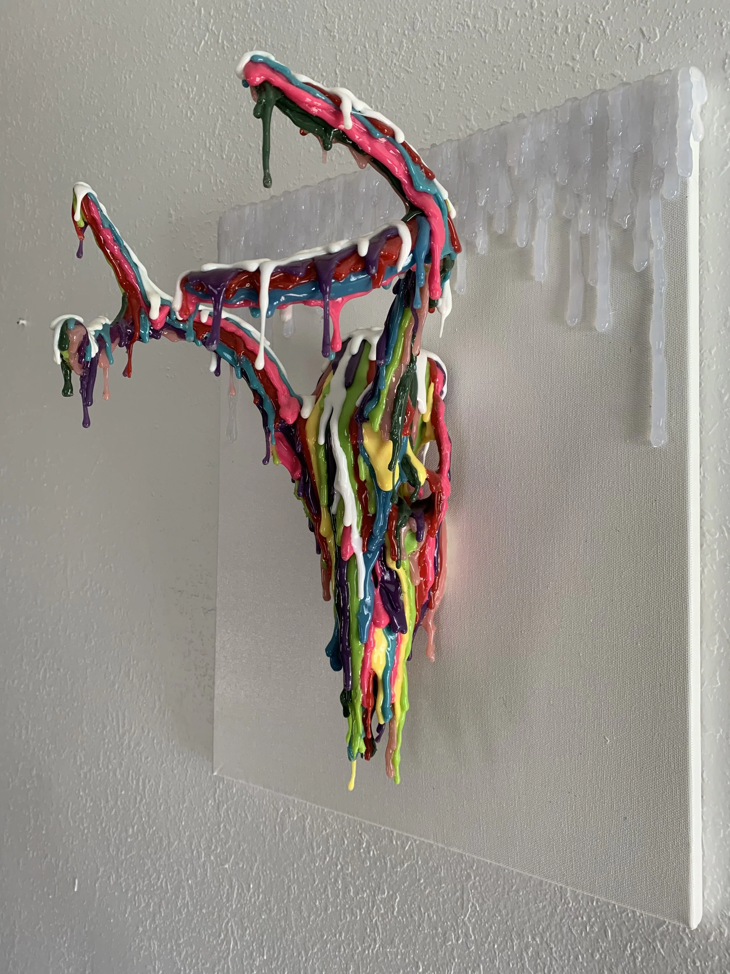 Colorful, abstract art sculpture with dripping paint on a canvas, protruding outward.
