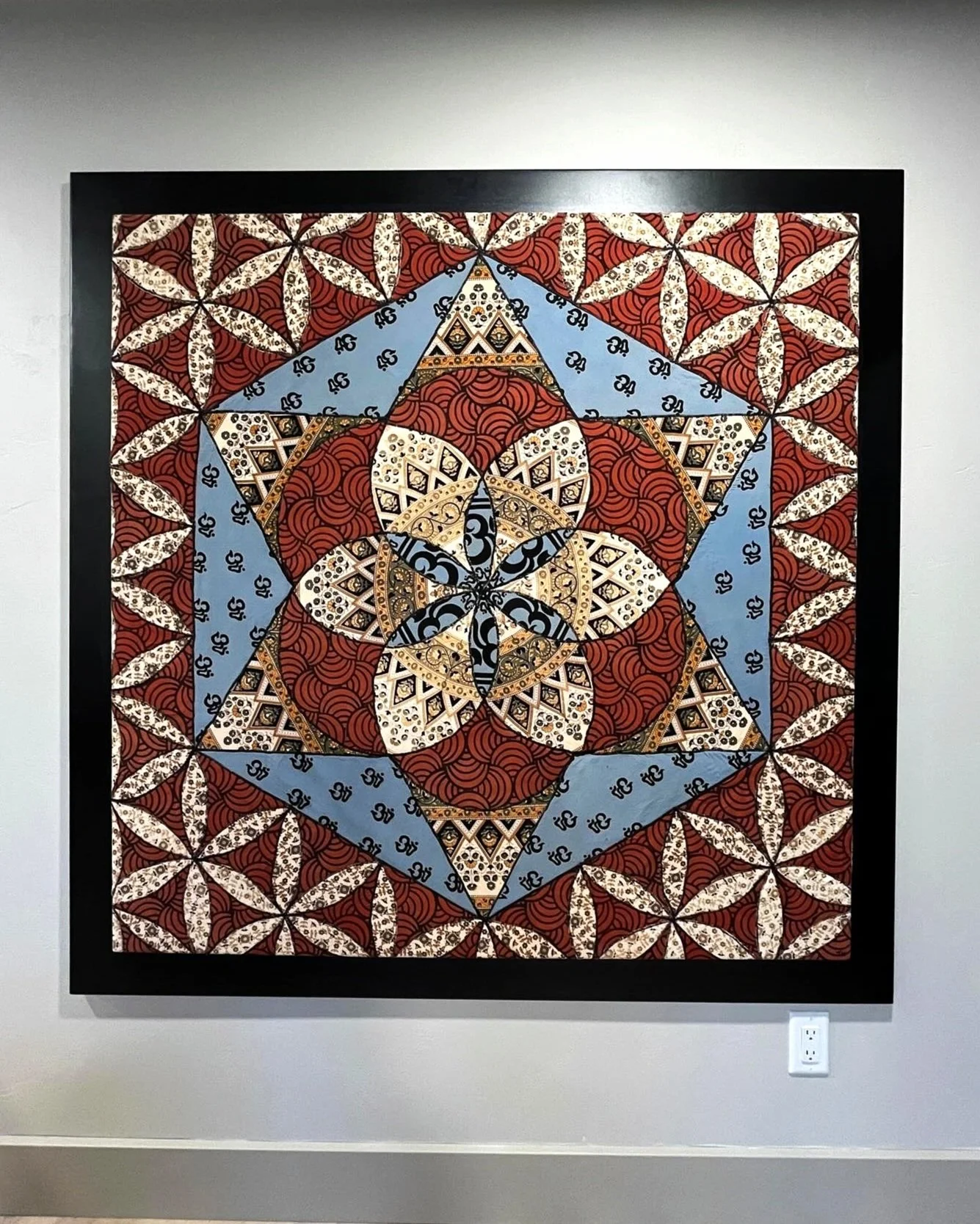 Intricate geometric artwork with star and floral patterns, featuring red, blue, and beige colors in a black frame.