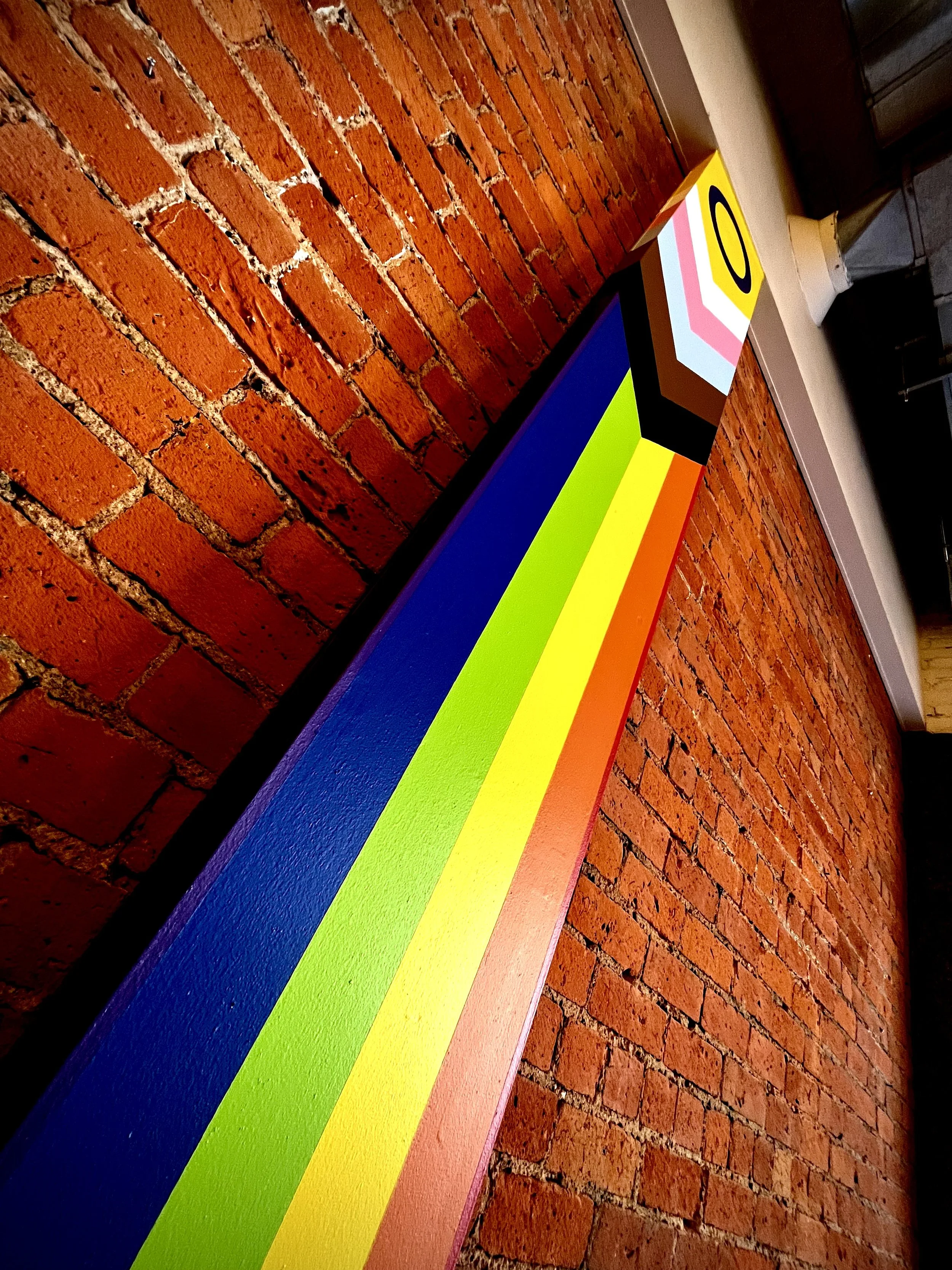 Colorful painting with rainbow stripes on a brick wall