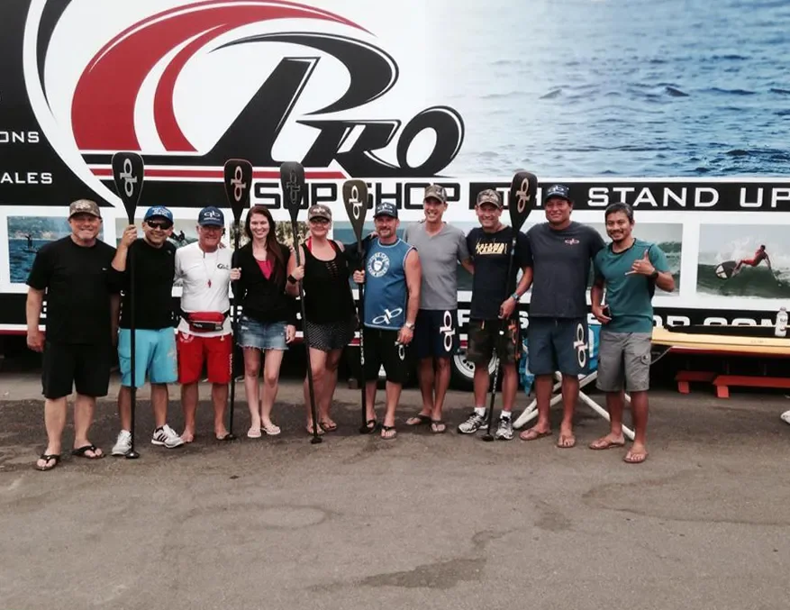 Group shot from clinic event at Pro SUP Shop led by Dave Kalama in 2014 at Pro SUP Shop. Coral Hine is standing next to Mike Vaughan Jr, with 4x Olympian Jim Terrell & SUP Pioneer Dave Kalama