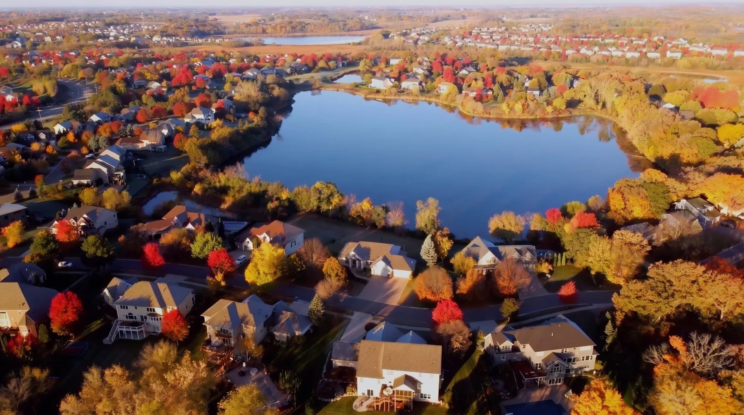 Aerial view of homes around a pond in the Watermark neighborhood of Victoria, MN in the fall