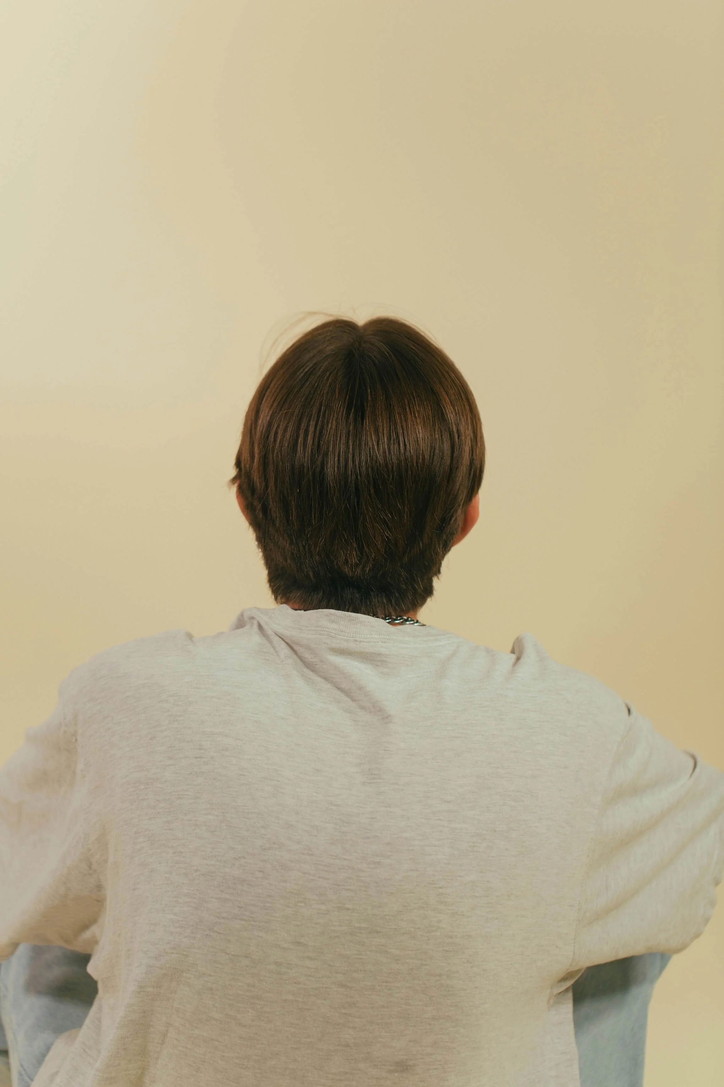 The back of a person's head, wearing a cream shirt (trauma therapy minneapolis)