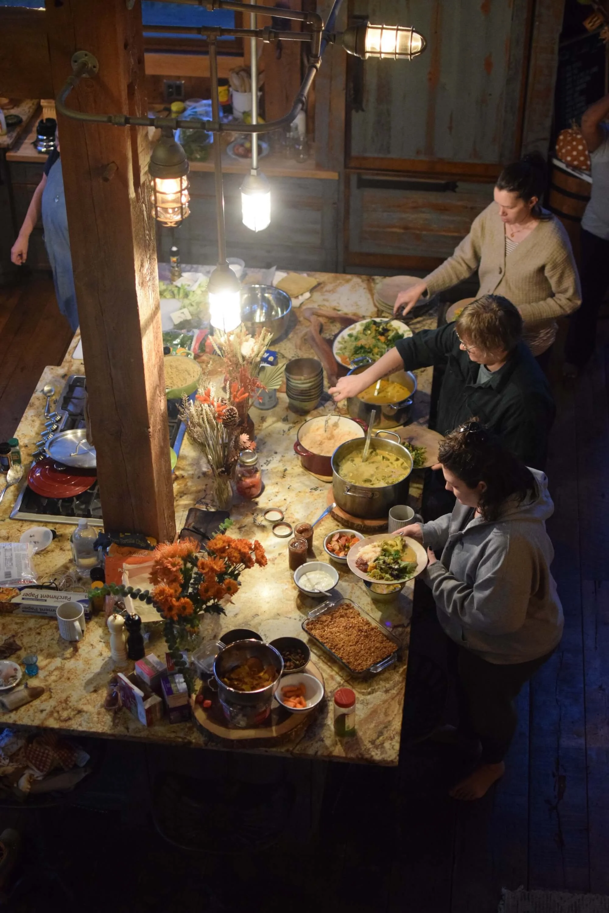 A line of people shares food in the kitchen retreat space