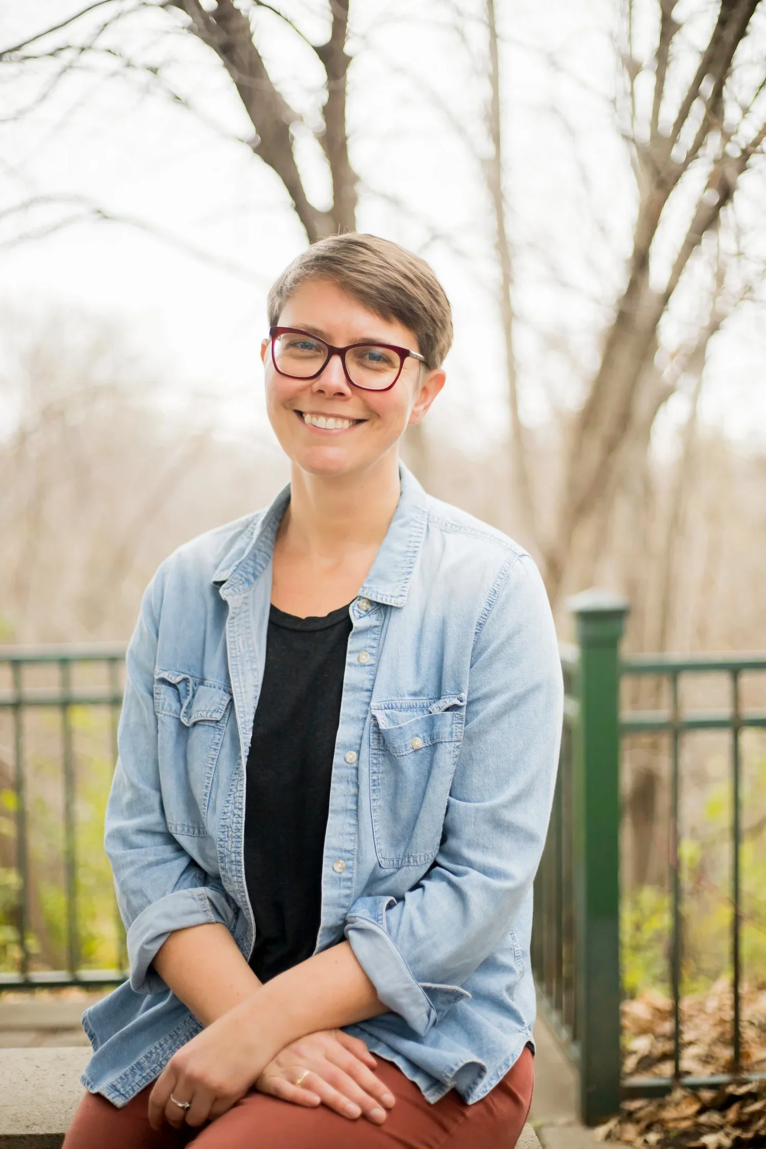 Ellie smiles at the camera in glasses a light blue button-up