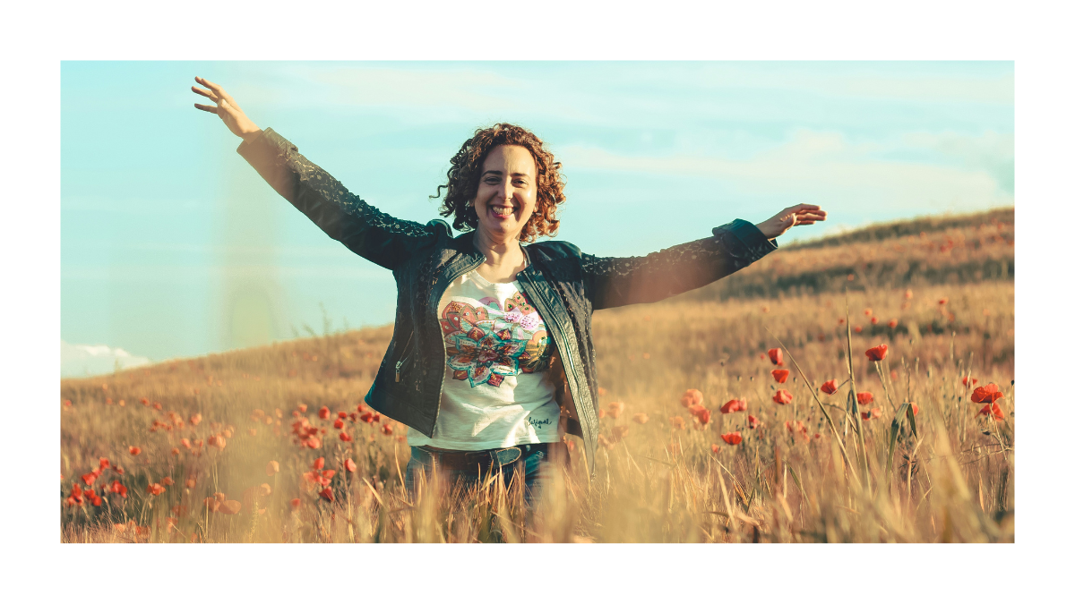 Woman standing confidently in an open field with arms outstretched, representing freedom, transformation, and confidence after weight loss.
