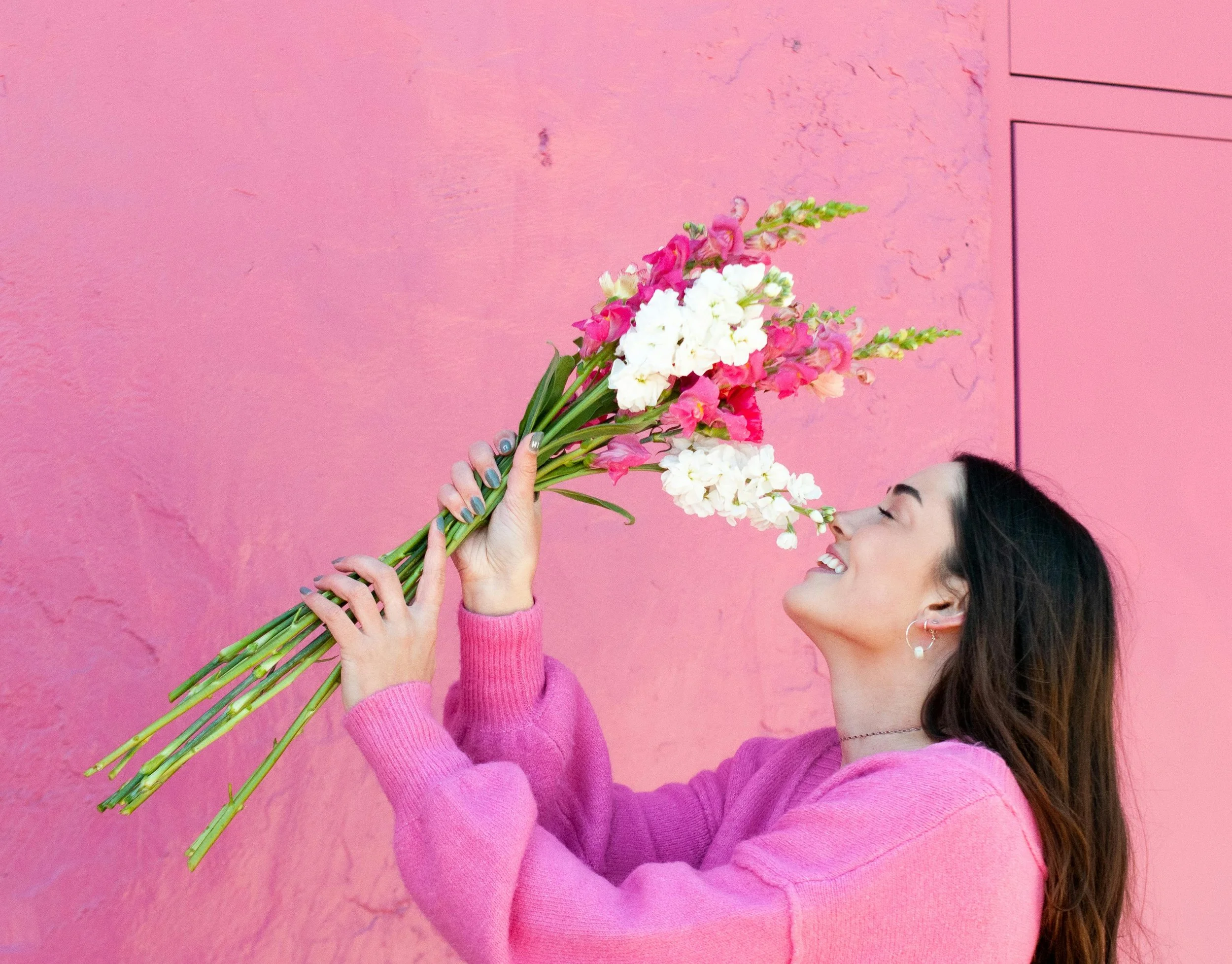 Woman smiling gently while holding fresh flowers, symbolizing self-compassion and personal growth in breaking free from bad habits.