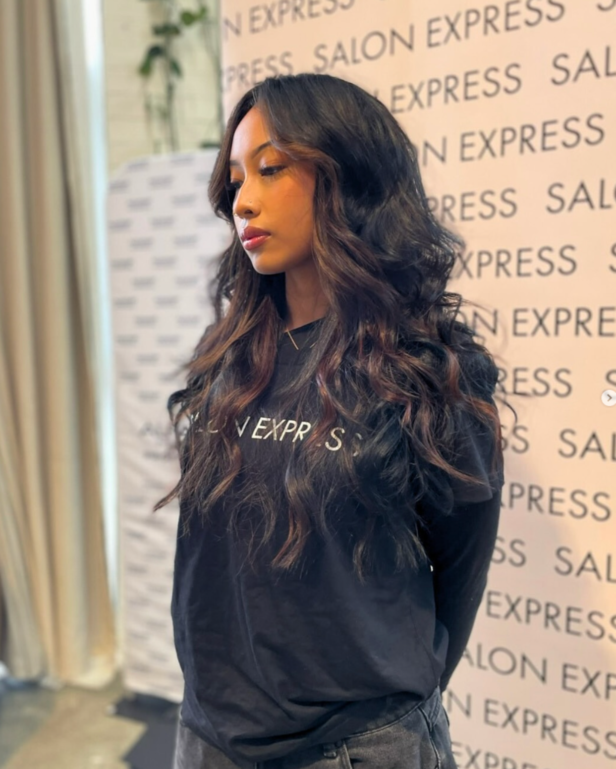 Woman standing in front of a "Salon Express" branded wall, wearing a black "Salon Express" shirt.