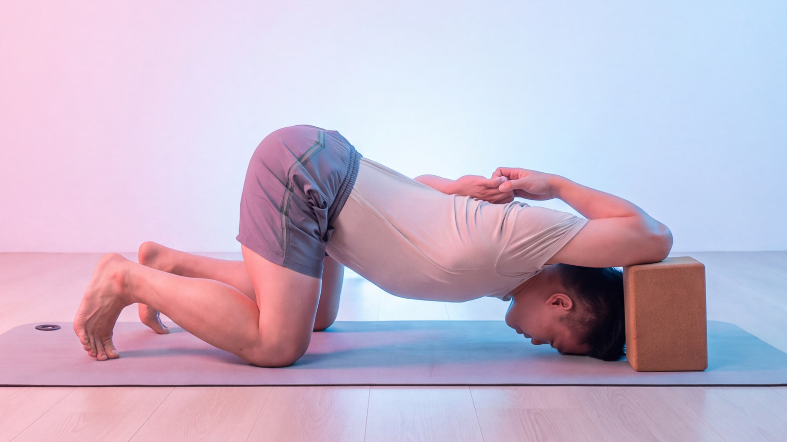 Man performing a supported shoulder-opening stretch with a yoga block on a mat.