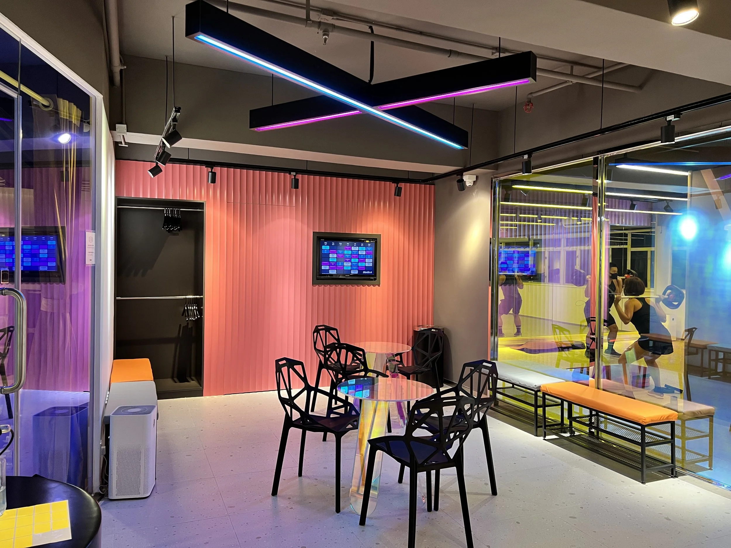 TeamX Taikoo lounge: Modern community space with class schedules and seating for members to connect before/after group fitness sessions.