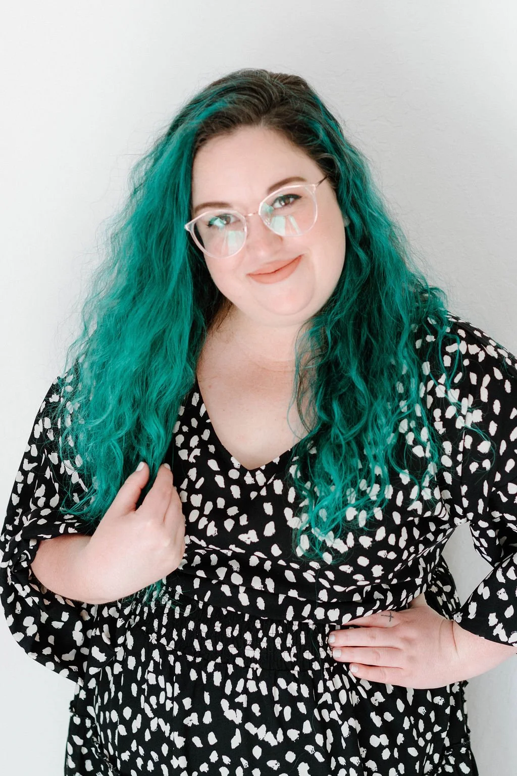Woman in dress with glasses and colorful hair smiling (Kristen)