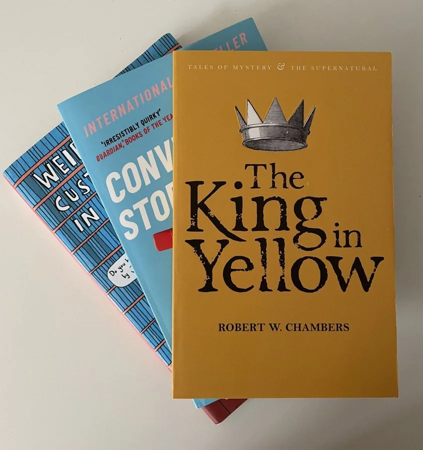 Photograph of a stack of books from overhead including The King in Yello, Convenience Store Woman and Weird Things Customers Say in Bookshops