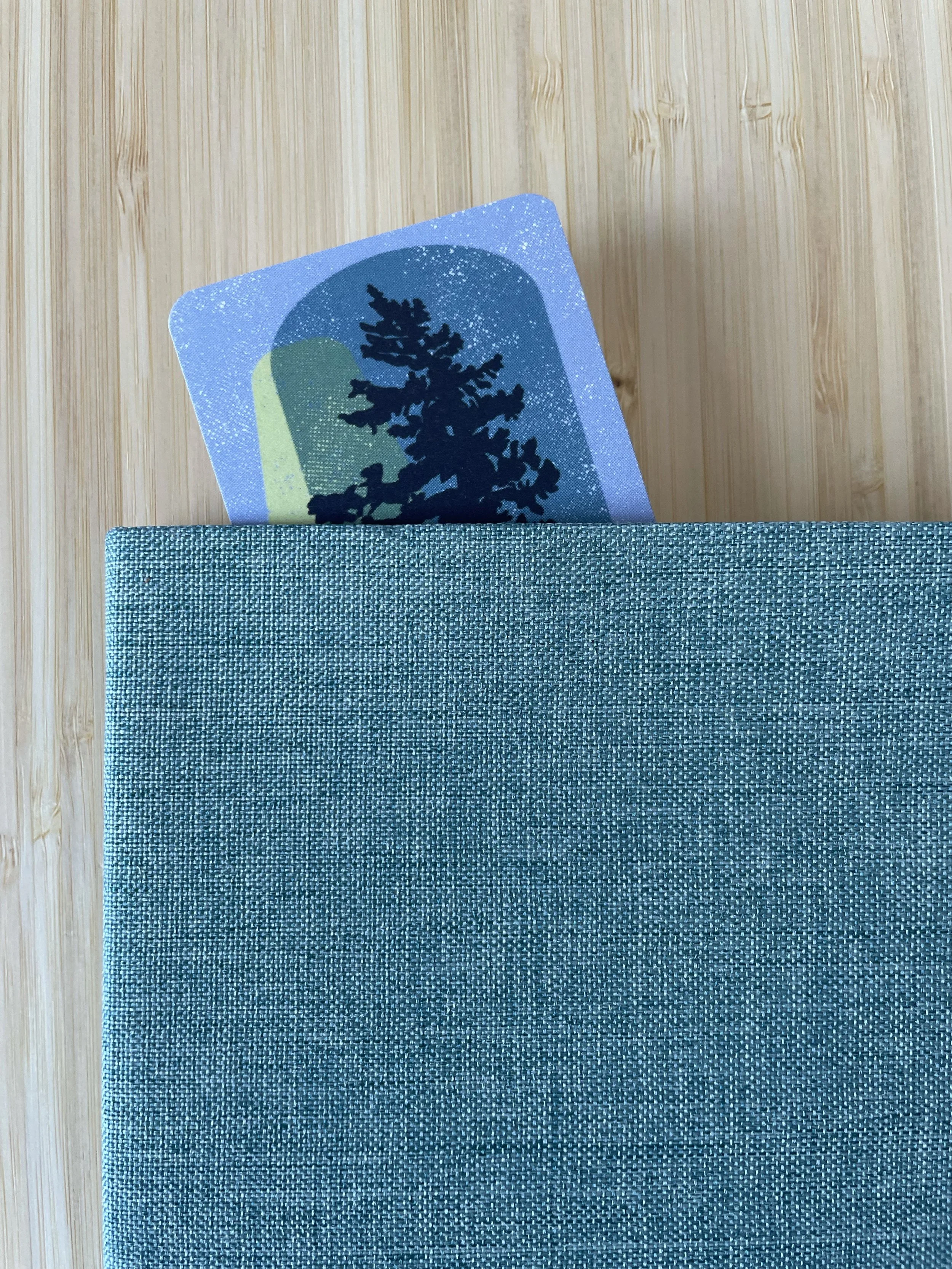The top of an evergreen playfully peeks out of a book.