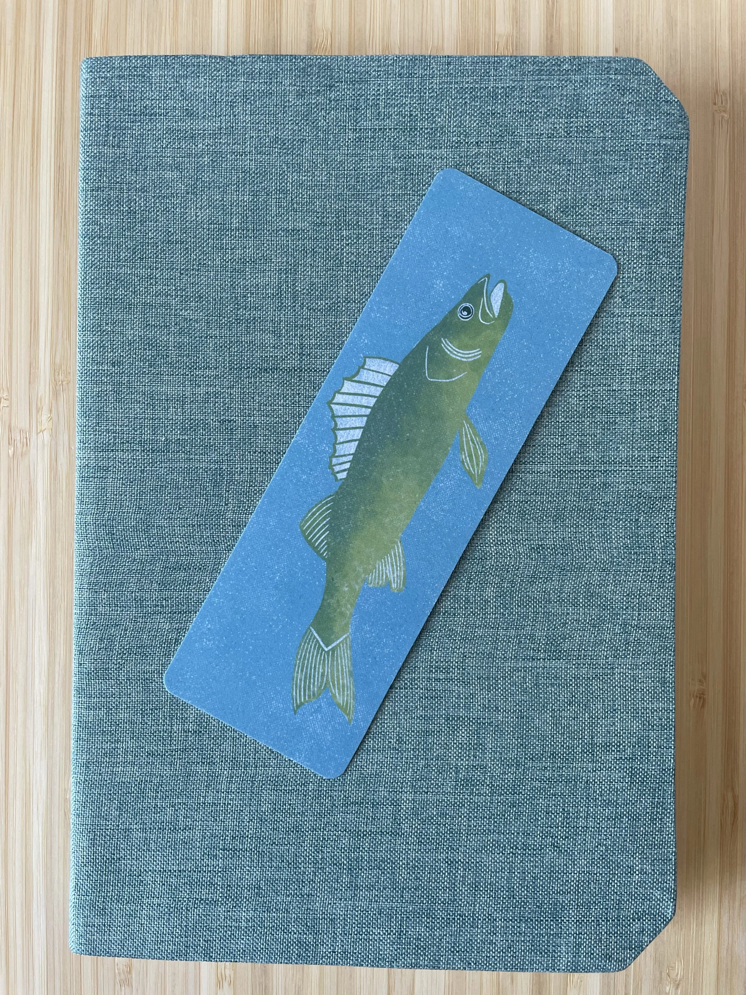 A fish bookmark sits atop of a light teal journal.